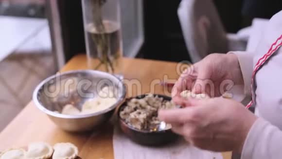 用肉馅包饺子时要紧紧抓住女人的手女厨师很快就会熟练地包饺子瓦雷尼基视频的预览图