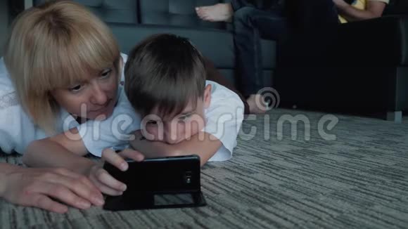 快乐的家人爸爸妈妈和儿子看电影玩手机和笔记本电脑游戏视频的预览图