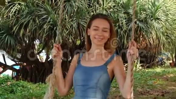 慢动作理发师年轻女子在海边的花园里摇摆视频的预览图