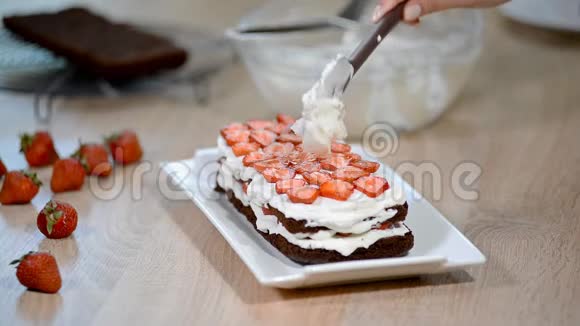 女人的手在草莓蛋糕上放生奶油视频的预览图
