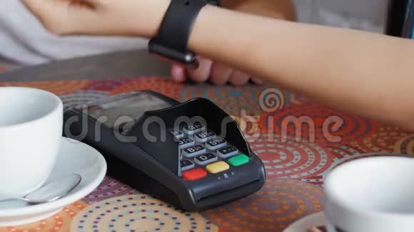 咖啡馆里的女商人用智能手表和终端机来支付价格视频的预览图