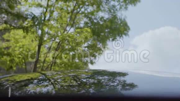 绿色的树和蓝色的天空反射在车顶上视频的预览图