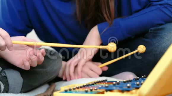 演奏音乐乐器特写男孩他用棍子在木琴上演奏他的老师坐在他附近视频的预览图