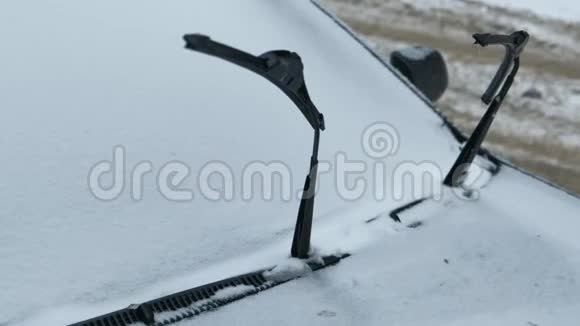 把车停在前面挡风玻璃雨刷在冬天远离被雪覆盖的窗户视频的预览图