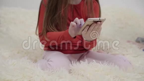 两个穿睡衣的小女孩在床上用智能手机视频的预览图
