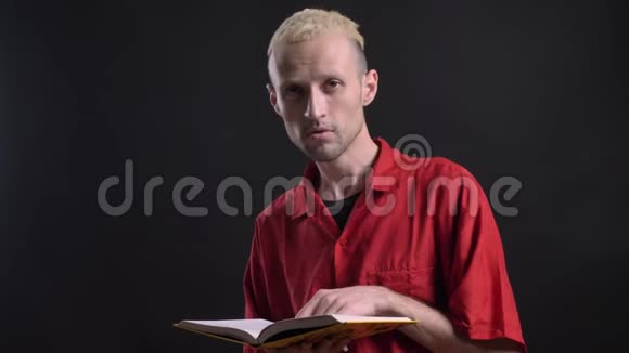 金发男人正在看书看着镜头微笑着黑色的背景视频的预览图