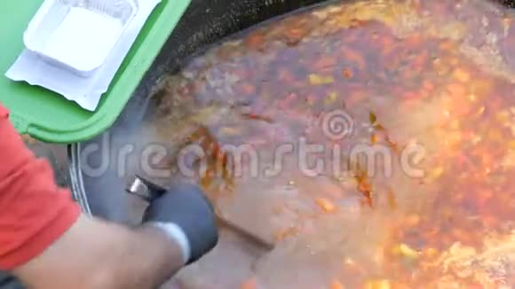 一大桶汤在街头美食场上厨师把汤倒进塑料罐子里视频的预览图