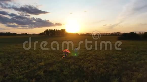 母亲和男孩带着风筝在绿色的田野上奔跑欢声笑语喜庆的心情秋天日落视频的预览图