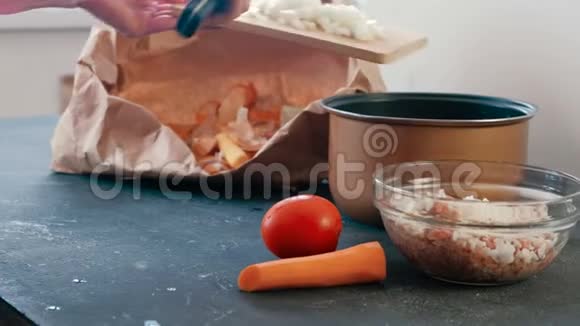 特写女人她的手在木板上切一个洋葱和西红柿然后放在平底锅里视频的预览图