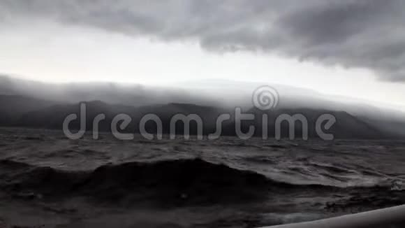 游艇上的背景是天空中的深灰色云和贝加尔湖上的风暴视频的预览图