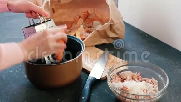特写的女人她的手在平底锅里的烤炉上搓胡萝卜视频的预览图