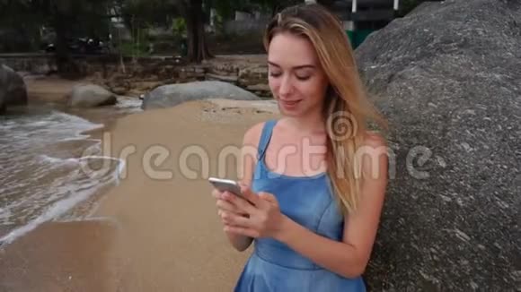 慢镜头摄影师女士使用智能手机在海边聊天视频的预览图
