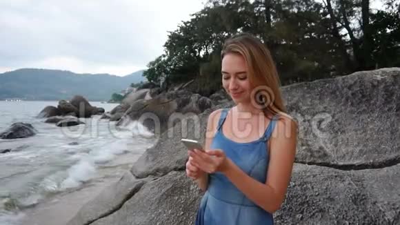 慢动作女律师在海边用智能手机散步视频的预览图