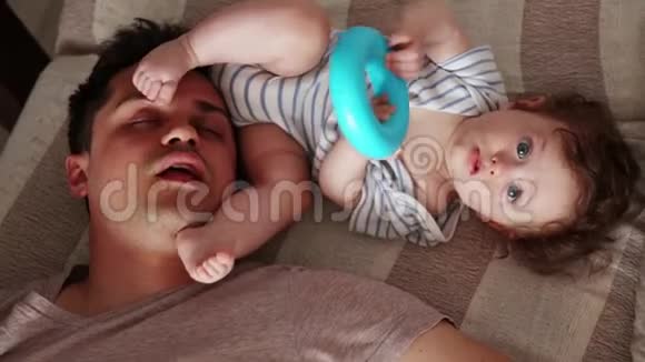 年轻疲惫的父亲睡在小孩身边视频的预览图