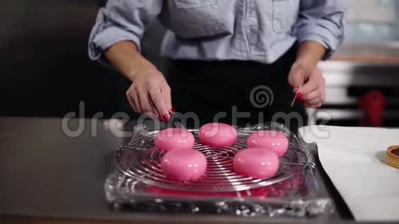 烹饪糕点小建筑的概念女性糖果师准备美味的现代甜点加粉色霜视频的预览图