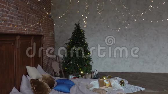 时尚的圣诞阁楼内部舒适的卧室木制床和许多灯与装饰圣诞树和一个视频的预览图