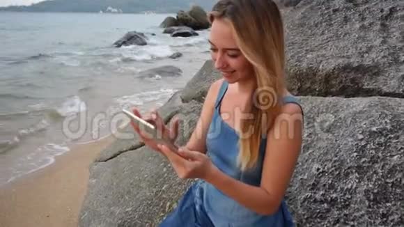 慢动作造型师女孩带着平板电脑在海边看照片视频的预览图
