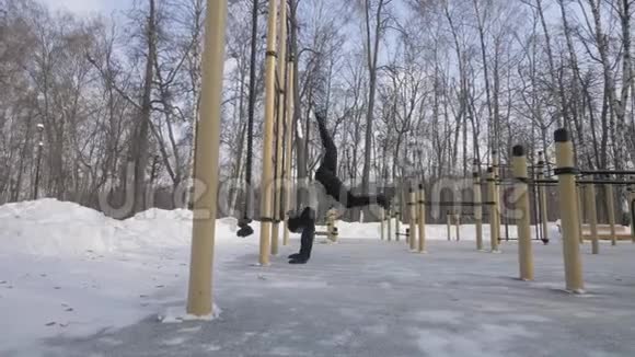 强壮的男子训练在冬季运动场上用双腿支撑运动视频的预览图