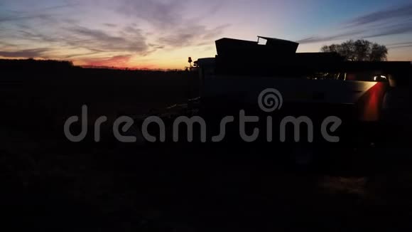 日落时分在田野上工作的联合收割机视频的预览图