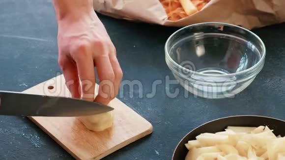 特写男人他的手在木板上切一个土豆然后把它放在一个油炸锅上视频的预览图