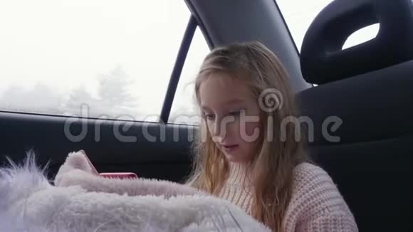 小女孩在车里用智能手机视频的预览图