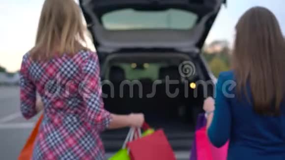 两个女人把购物袋放在车的后备箱里坐在里面然后开车走视频的预览图