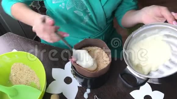 女人在模子里加蛋羹做一个饼干面包屑和牛奶果冻蛋糕视频的预览图