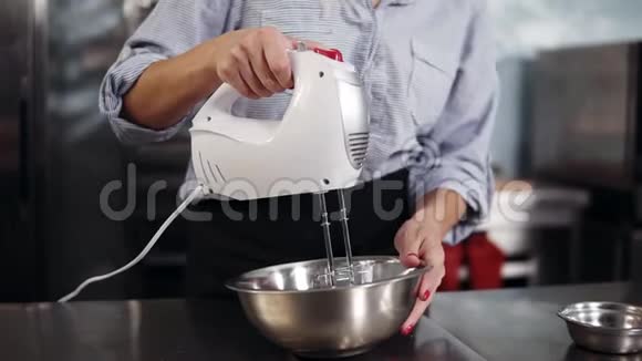 在钢碗里把蛋清混合起来使用手持搅拌器搅拌的女性糖果视频的预览图