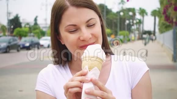 在户外享受软冰淇淋锥的女人一个人在街上吃冷冻酸奶的女性旅行者视频的预览图