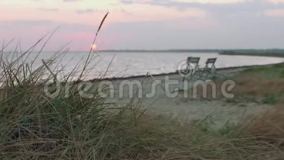 看着海面上模糊的日出和前面集中的草地焦点从前景转移到背景视频的预览图