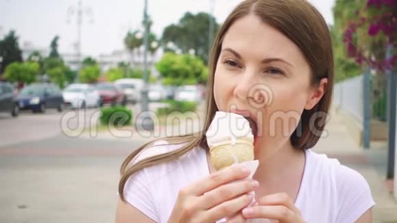 在户外享受软冰淇淋锥的女人一个人在街上吃冷冻酸奶的女性旅行者视频的预览图