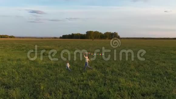 母亲和男孩带着风筝在绿色的田野上奔跑欢声笑语喜庆的心情秋天日落视频的预览图