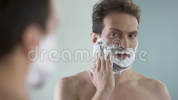 准备刮胡子的男人因为剃须泡沫而感到面部不适和刺痛视频的预览图