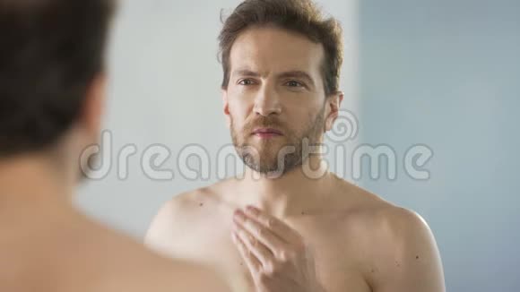 中年男子用镜子批判性地看着他的胡子早晨的仪式视频的预览图