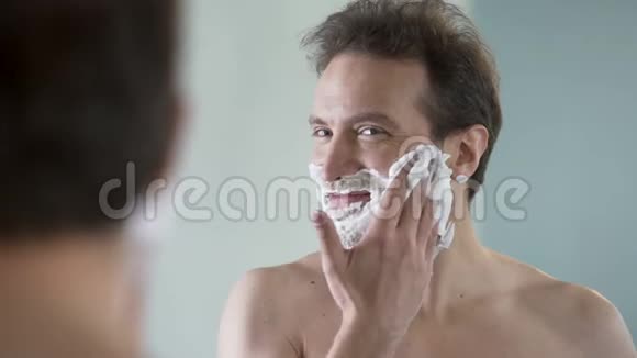 快乐自信的男性在刮胡子前把剃须膏涂在脸上视频的预览图