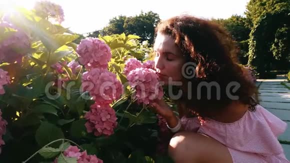 在花园里闻到花香的年轻女子视频的预览图