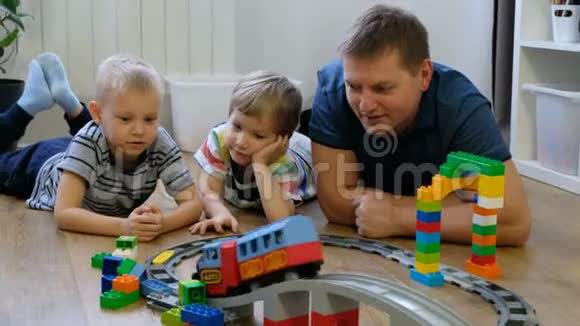 家庭观念孩子们和爸爸在木地板上玩火车父亲有儿子视频的预览图
