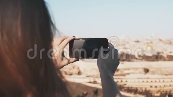 女孩拍摄以色列耶路撒冷的智能手机照片在阳光明媚的日子里女性手拿着电话捕捉瞬间4K视频的预览图