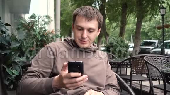 坐在街边咖啡馆里看智能手机的人视频的预览图