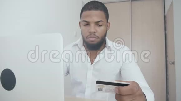 非洲年轻人在家用笔记本电脑上网购物视频的预览图