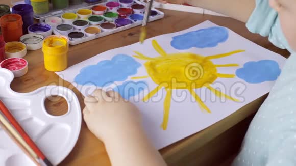 年轻女孩画着黄色的太阳和蓝色的云视频的预览图