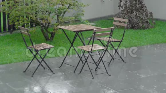 大雨在后院和潮湿的家具上倾盆大雨一张桌子和一张桌子视频的预览图
