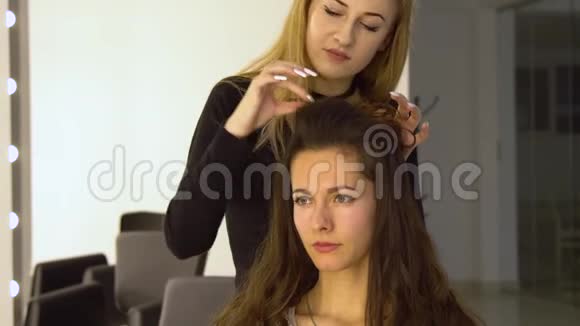 美容院的年轻漂亮女孩理发师发型师使女孩头发理发师用一个视频的预览图