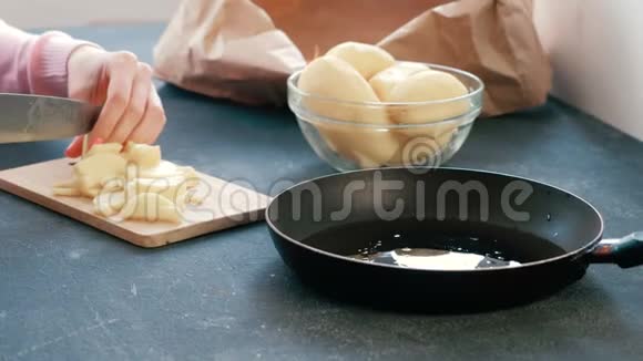 特写女人她的手在木板上切一个土豆然后把它放在一个油炸锅上视频的预览图