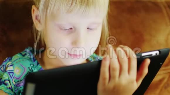 一个金发女孩在数码平板电脑上玩耍的肖像视频的预览图