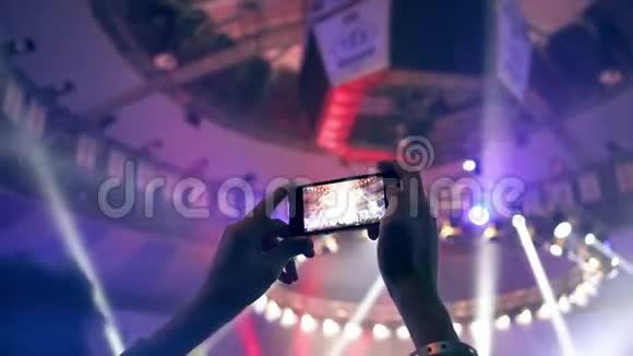 一个年轻人用智能手机在音乐会上射灯视频的预览图