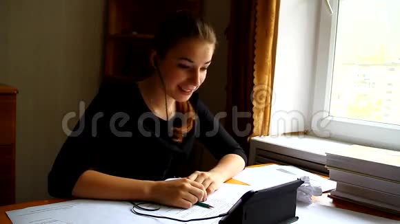 年轻的女学生坐在书桌前和朋友聊天视频的预览图