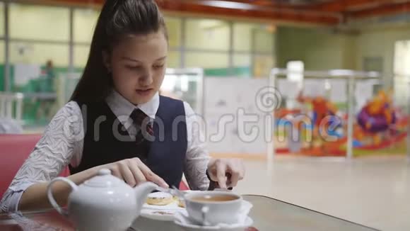 穿着校服的少女坐在学校食堂的桌子旁吃蛋糕喝茶视频的预览图
