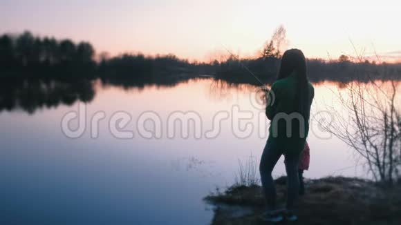 傍晚日落时分妈妈和女儿在池塘边钓鱼视频的预览图