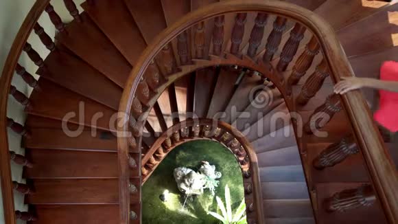 穿着粉红色裙子的女人下来爬上一个绿色植物和喷泉的圆形楼梯4k视频的预览图
